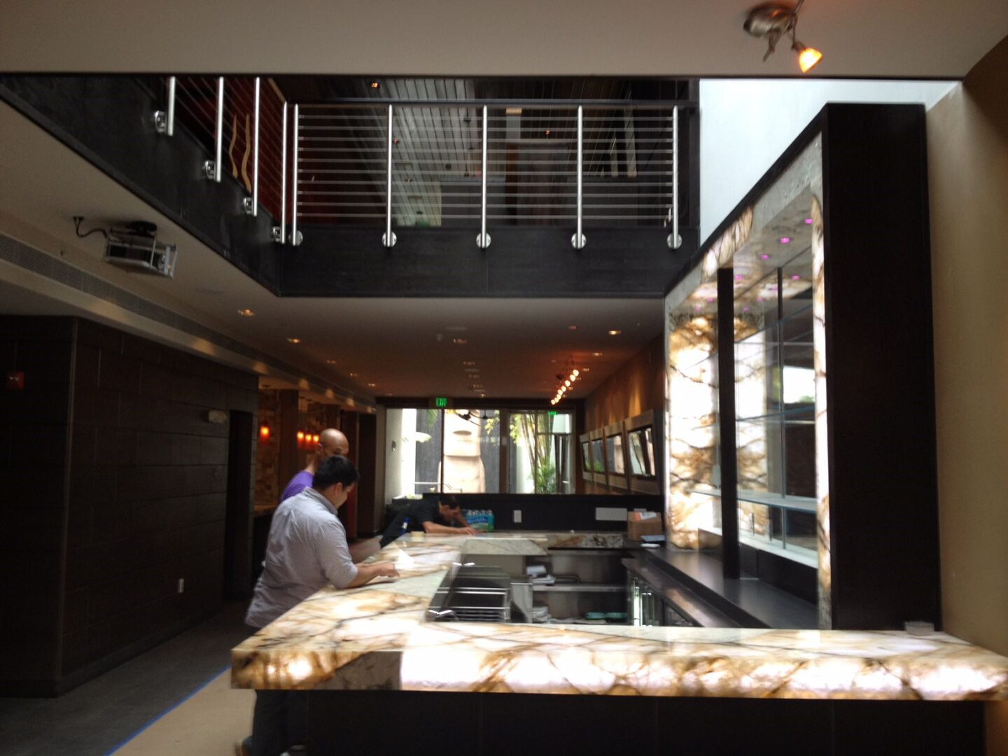 Restaurant bar with backlit onyx panels, cable railings and mezzanine