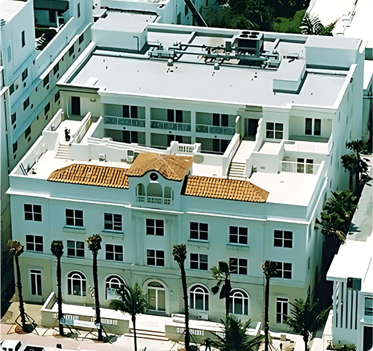 Aerial view of a completed white building with barrel tile roof and rooftop terraces