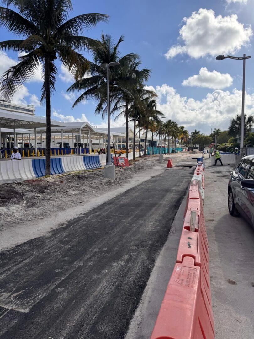 Roadway and terminal work at PortMiami with traffic control barriers and cruise terminal behind