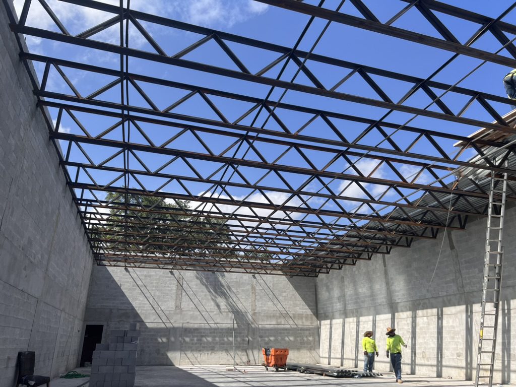 Steel roof trusses spanning concrete block walls with crews below