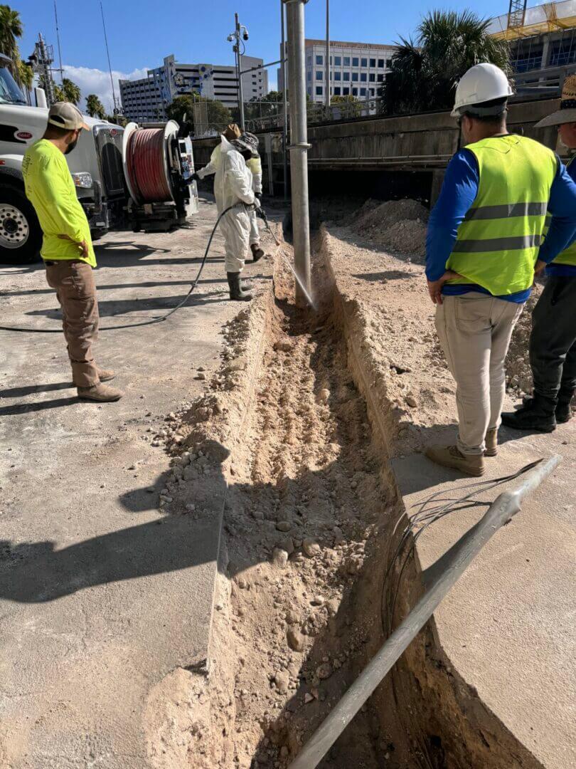 Crew installing and lining pipe in an open trench on an urban site