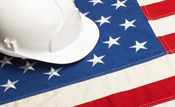 A white hard hat sitting on top of an american flag.