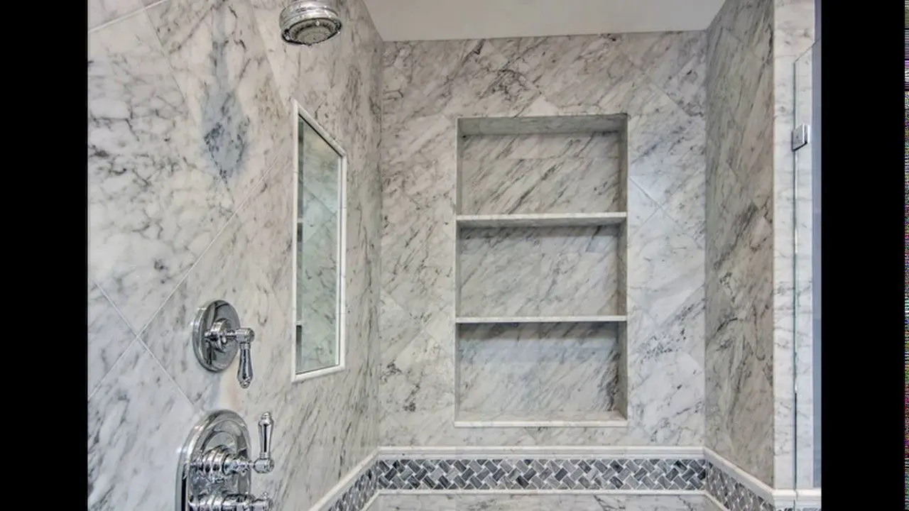 A bathroom with marble walls and floors, and a shower.